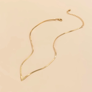 Detalle macro de un colgante en V dorado con cadena de serpiente plana y cierre ajustable