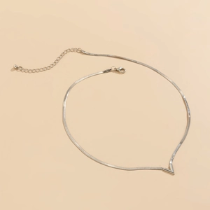 Detalle de una cadena de serpiente plateada con un acento metálico minimalista en forma de V