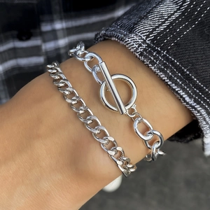 Close-up of dual silver chains with T-bar clasp worn over a dark checkered shirt