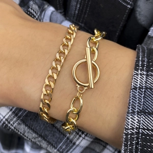 Close-up of golden flat Cuban chain and oval link bracelet with OT toggle clasp