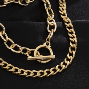 Detail of a golden double-layered flat Cuban chain bracelet with a classic OT clasp
