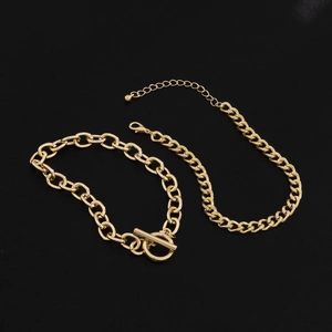 Detail of gold layered flat chain with OT toggle clasp and lobster buckle on black background