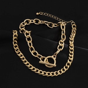 Detail of gold double-layer chain necklace with OT buckle on black silk background