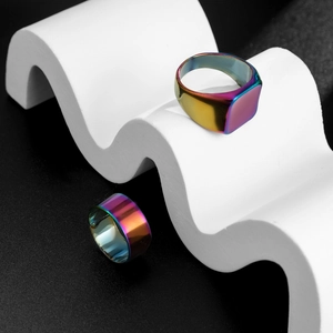 Close-up of rainbow plated stainless steel square signet ring set on artistic white waves