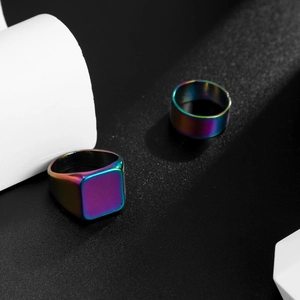 Detail of two rainbow plated square signet rings with iridescent metallic finish on black