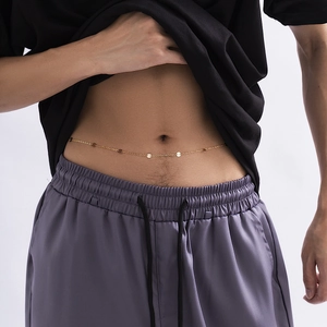 Close-up of golden metal waist chain with round sequins on a male model with gray background