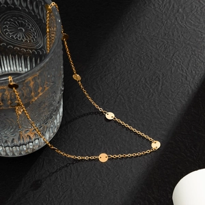 Close-up of golden metal waist chain with round sequins draped on a glass edge