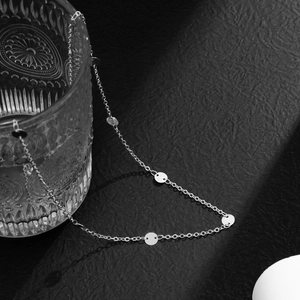 Detailed close-up of a minimalist silver metal waist chain with flat circular sequins