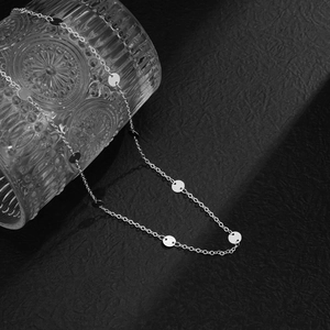 Macro shot of silver metal sequins on a minimalist waist chain against a black texture