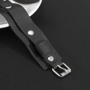 Dettaglio del cinturino in pelle nera con borchie in argento e fibbia regolabile