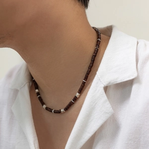 Close-up of bohemian beaded necklace with dark wood beads and silver accents on a male model
