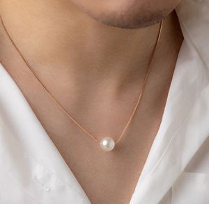 Nahaufnahme einer eleganten weißen Perlenkette mit goldener Schlangenkette am Model