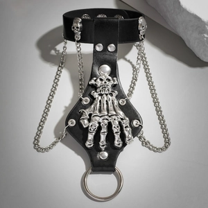 Détail d'un bracelet gothique en cuir avec main de crâne argentée, chaîne et anneau