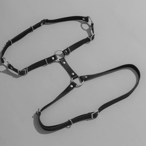 Macro shot of punk black leather body harness with silver metal rings and rivets