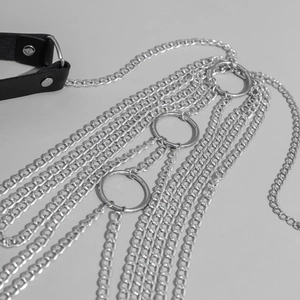 Close-up of layered silver punk body chains with leather straps and metal rings detail