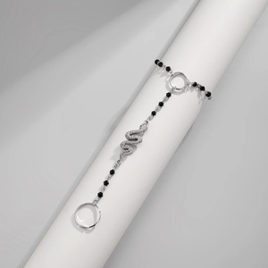 Detailed close-up of a silver snake-shaped bracelet with black diamond beads on a stand