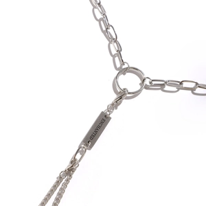 Detail of silver stainless steel body chain with ENCHANTED engraved rectangular tag