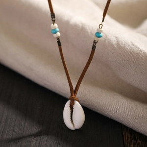Detalle de un collar con colgante de concha blanca natural y cuentas azules decorativas