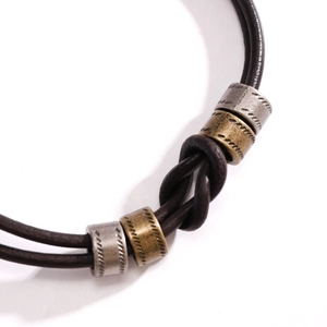 Macro di bracciale in pelle marrone a doppio filo con cilindri in metallo vintage