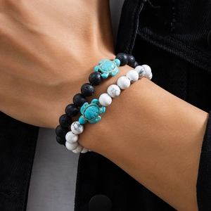 Detailed close-up of beaded bracelets featuring black lava stones and turquoise turtles
