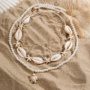 Détail du collier de perles tortue de mer avec coquillages et étoile de mer sur le sable