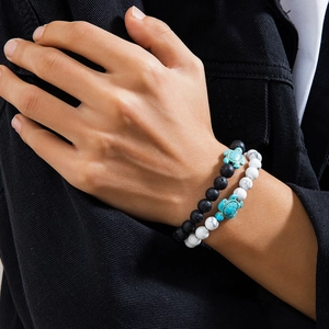 Close-up of beaded bracelets with turquoise turtle charms on black lava and marble stones