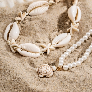 Détail du collier de perles de coquillage avec pendentif tortue blanche sur le sable
