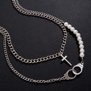Hip hop handcuff and pearl necklace with silver cross pendant on black background