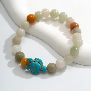 Detailed shot of beaded bracelet featuring a blue turquoise turtle charm on white wave decor