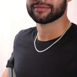 Close-up of a silver cuban link chain worn by a male model with a black t-shirt