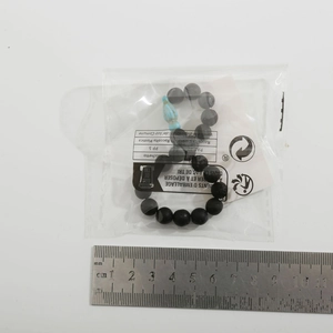 Detailed view of beaded tortoise bracelet with black stones and a blue bead beside a ruler