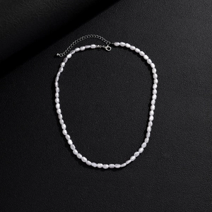 Baroque pearl necklace with silver lobster clasp on black textured background