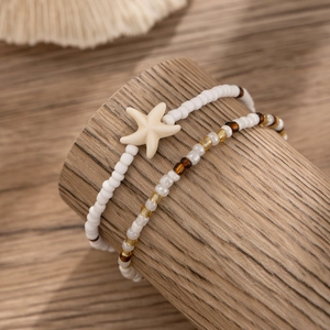 Detail view of Bohemian white beaded anklets with a starfish charm on a wooden stand
