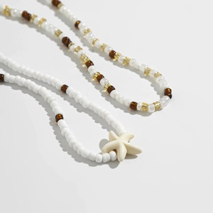Close-up of bohemian style beaded anklet featuring a white starfish charm and mixed beads