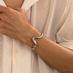 Detail of an irregular wave silver liquid metal cuff bracelet with a matte textured finish