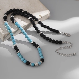 Dettaglio macro della collana da uomo in pietra vulcanica con perle turchesi e charm argento