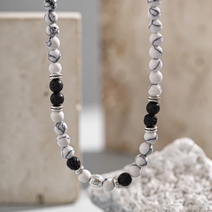 Vista macro di una collana di perle in pietra lavica e turchese bianco con inserti in metallo
