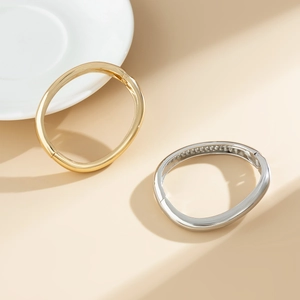 Dettaglio di bracciali a cerniera in oro e argento lucido con design minimalista