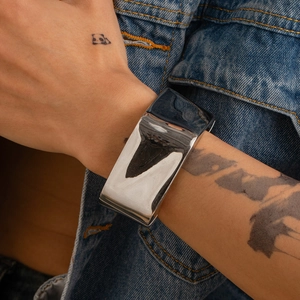 Bracciale rigido in metallo argento lucido al polso con design aperto e minimalista