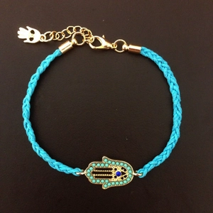 Blue braided rope bracelet featuring a golden Hamsa hand charm and adjustable chain