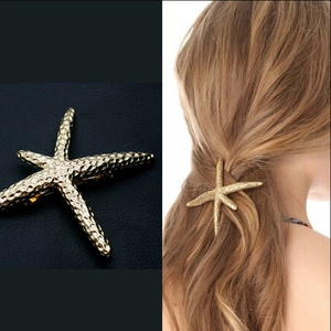 Macro view of gold starfish metal hair clip showing realistic texture on curly hair