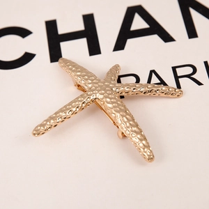 Detailed macro view of gold starfish hair clip featuring a unique hammered metal texture
