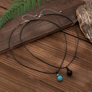 Minimalist wax cord necklace set with turquoise and black bead pendants on wood background