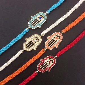 Detailed macro view of four colorful braided Hamsa Hand bracelets on black background