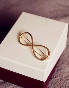 Close-up of a golden infinity symbol hair clip on a gift box background