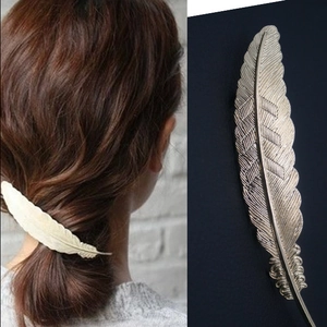 Detail of metallic feather hair clips in gold and silver showing realistic leaf textures