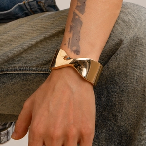 Dettaglio del bracciale rigido dorato irregolare da uomo indossato al polso