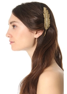 Close-up of a golden feather hair clip worn by a model to show intricate metallic textures