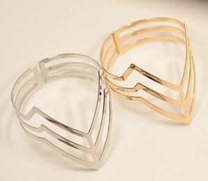 Detail of minimalist gold and silver cutout geometric V-shaped open arm cuffs
