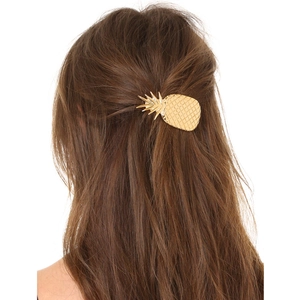 Detail of a golden pineapple hair clip with metallic texture on dark brown hair